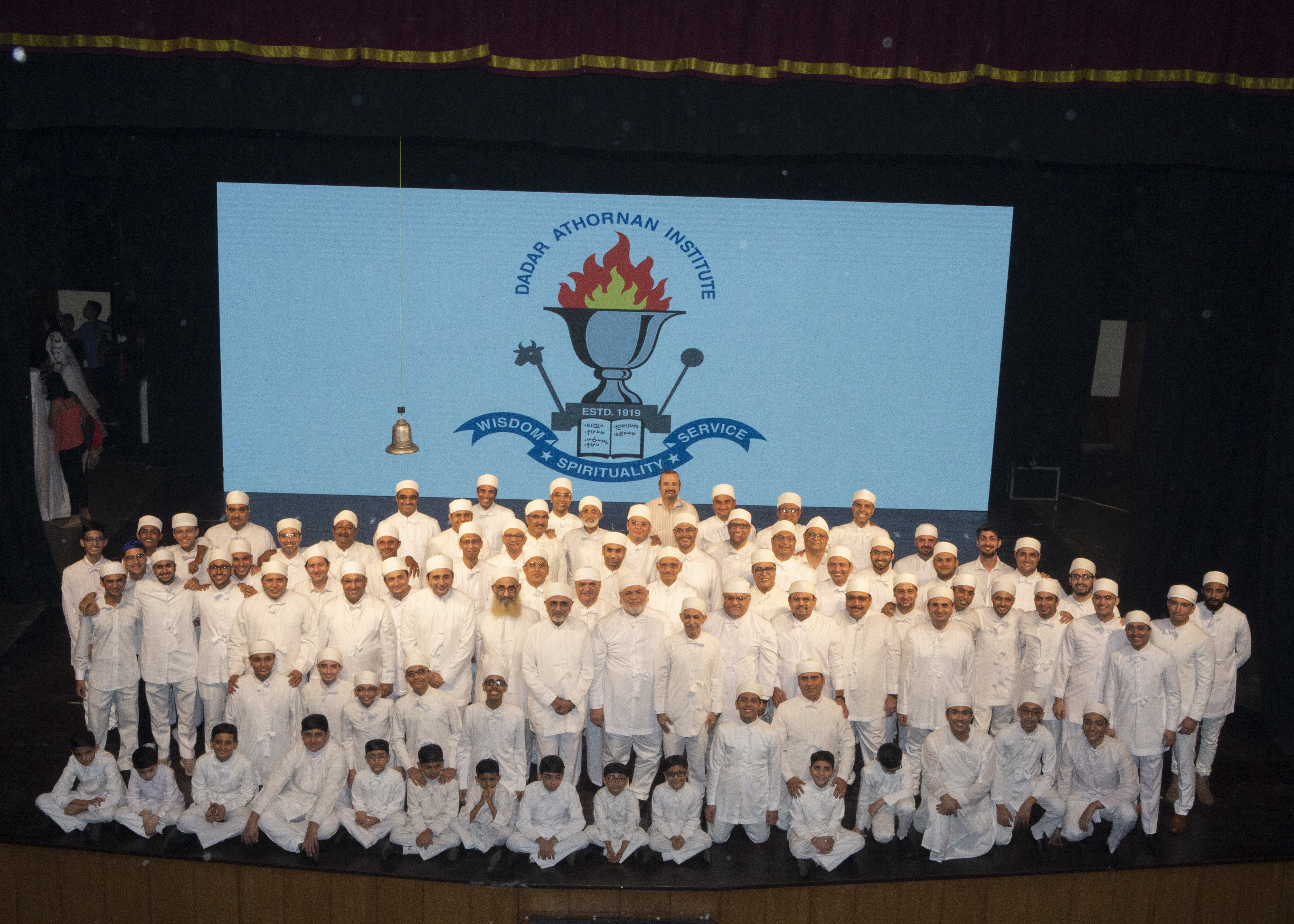 Students and faculty in traditional priestly dress at an Institute gathering on stage